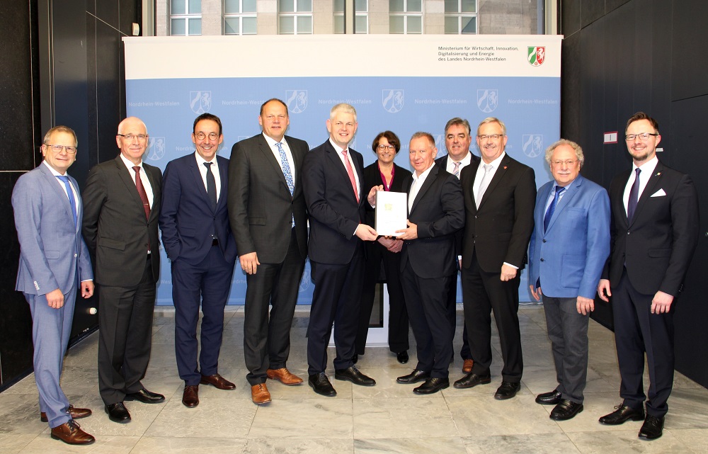Staatssekretr Christoph Dammermann (5. v.l.) nimmt den Abschlussbericht zur FUTURE SITE InWEST von Landrat Stephan Pusch (5. v.r.) als Sprecher der Delegation aus dem Kreis Heinsberg entgegen.